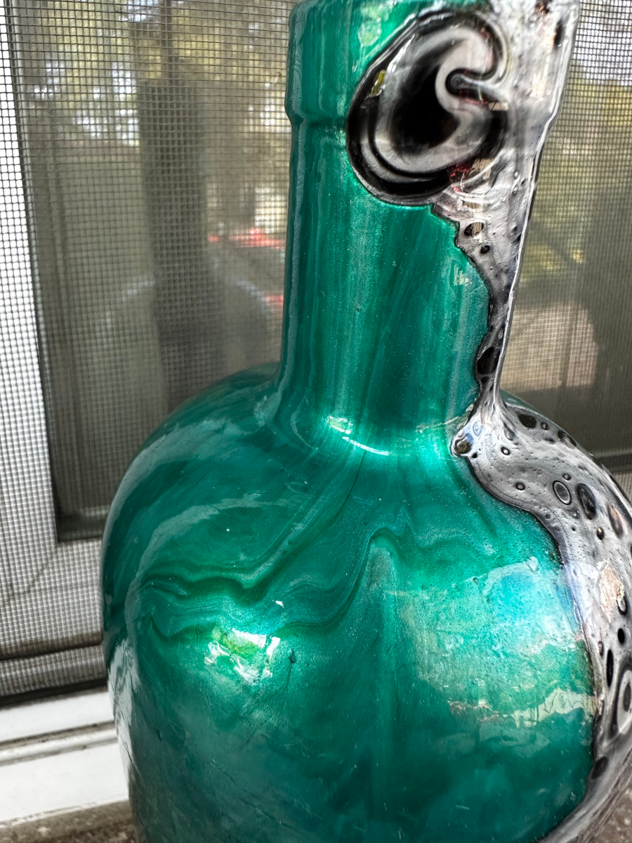 Neck and shoulder of the whisky bottle — green glass where the pour began, black and silver skin at the shoulder