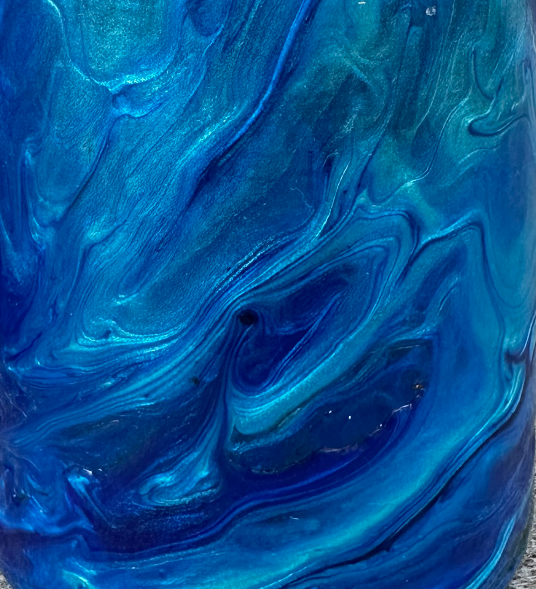 Close-up of the candle jar surface — deep blue swirling marbled pattern