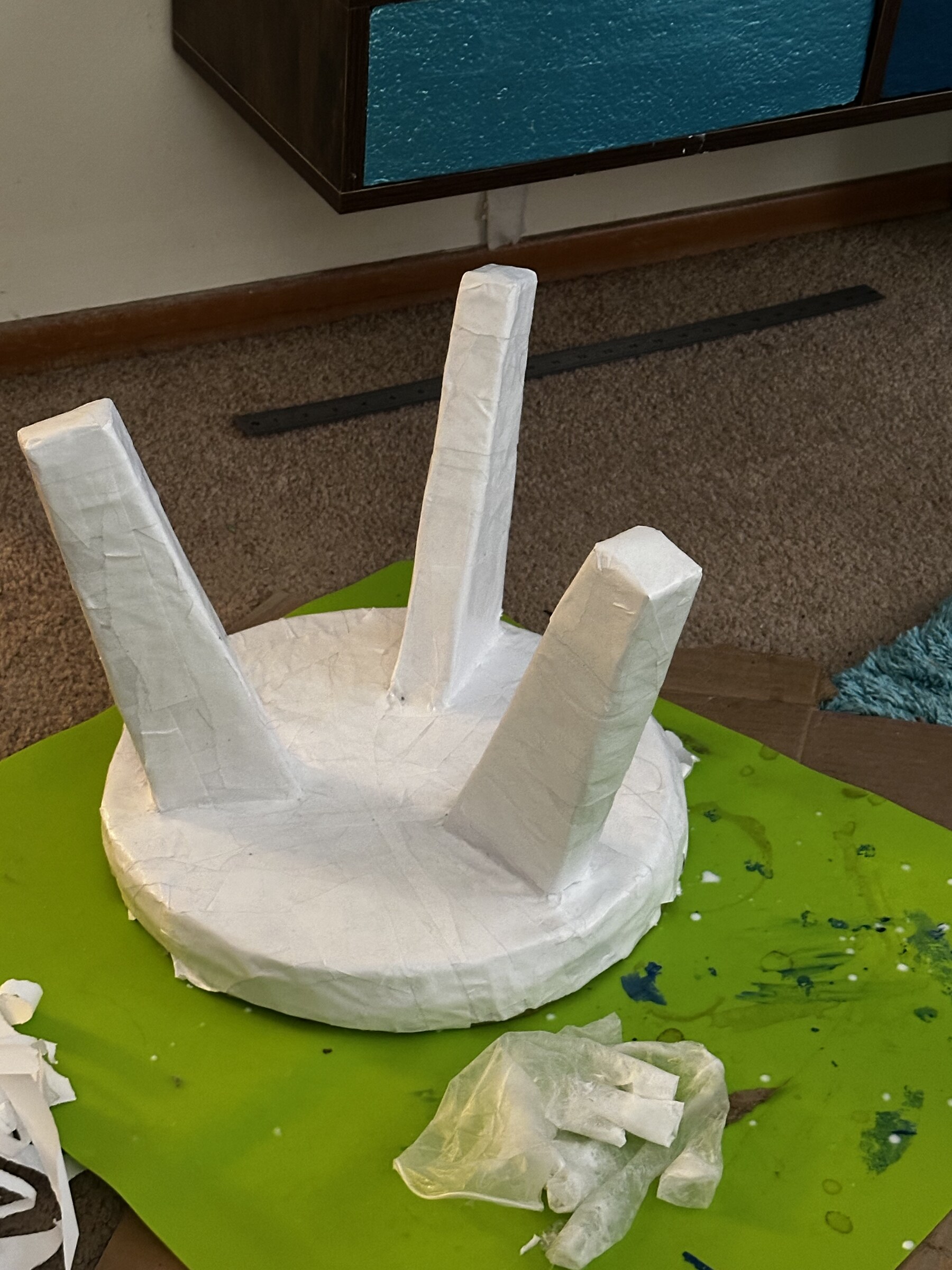Plant stand covered in white paper mache, upside down while drying