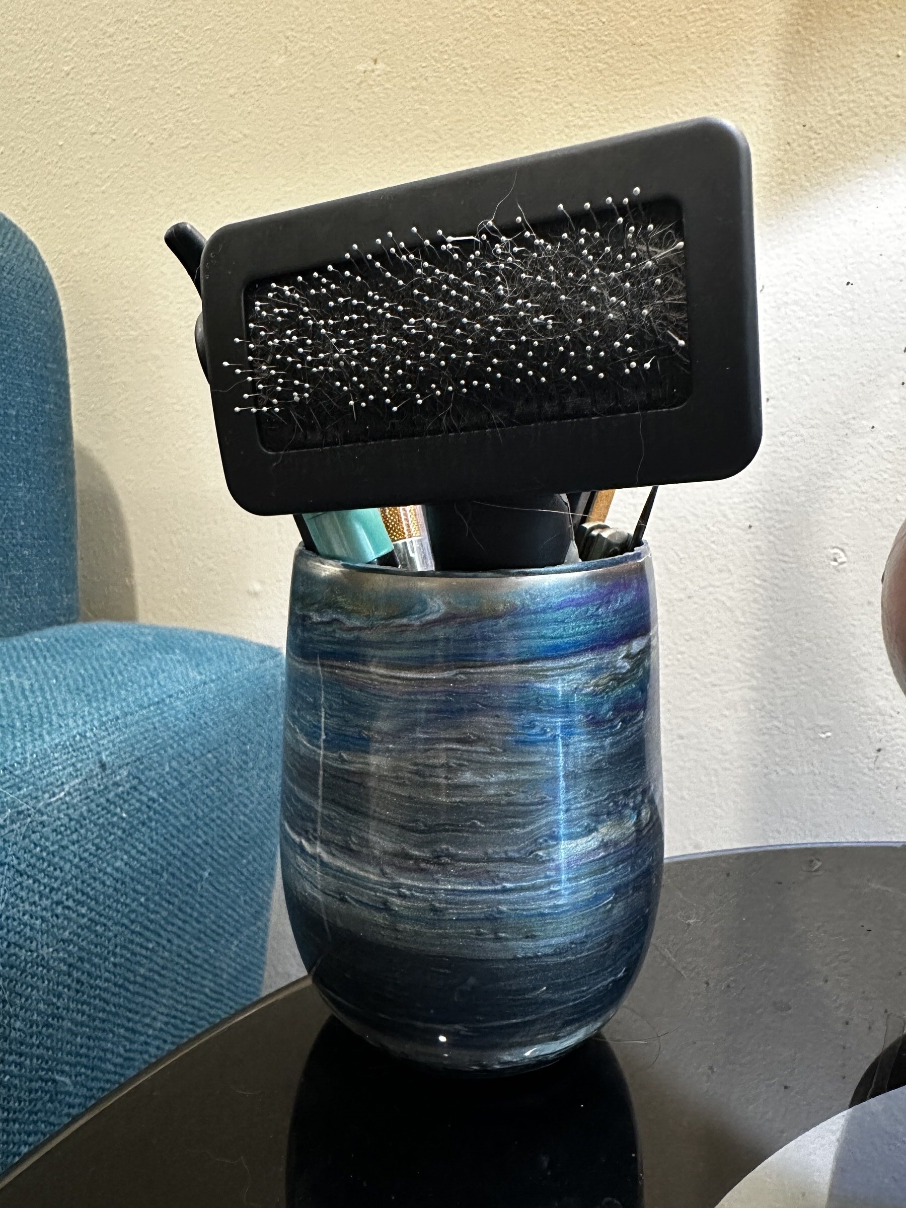 Resin cup in use on side table holding pens and Pax's grooming brush
