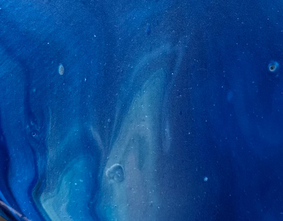 Close-up of the round canvas surface — metallic blues radiating from center without a horizon line