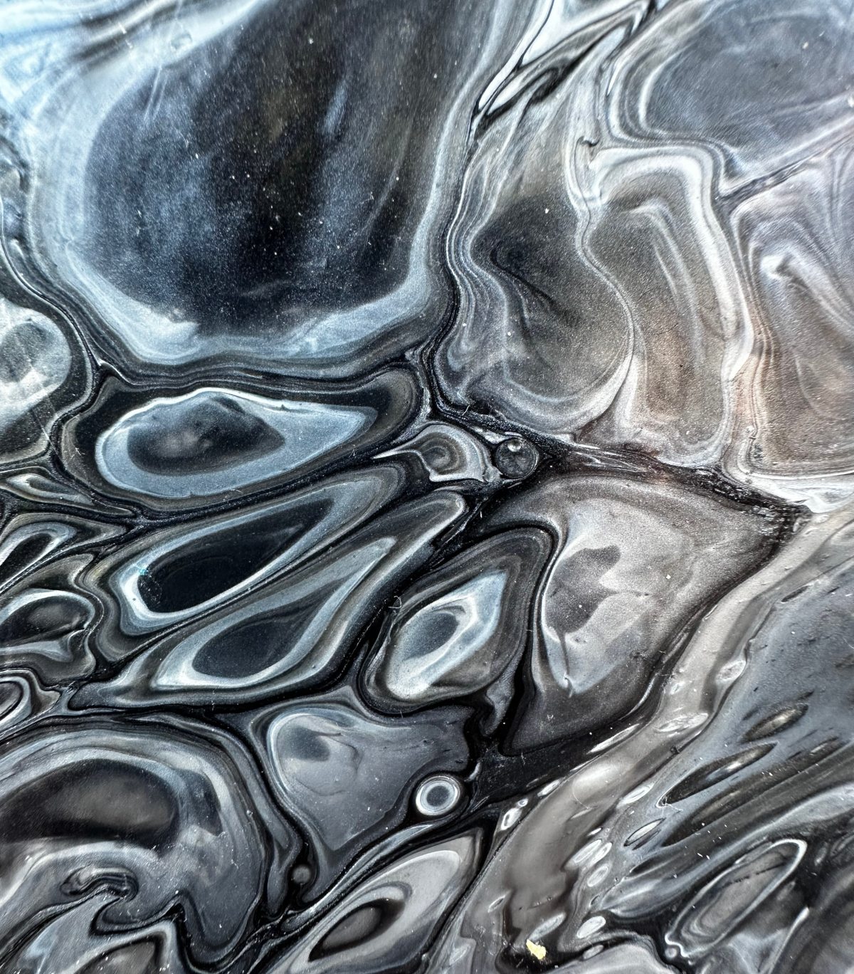 Close-up of the black and silver fluid pour surface showing swirling voids